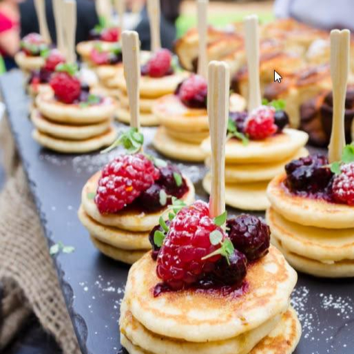 Platter of mini pancakes with powdered sugar and berries